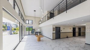 Una hall d'hotel moderna con pavimento in marmo, una reception e vista sull'esterno.