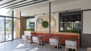 Un caffè moderno con un'area salotto con panche di legno, tavoli e sedie.