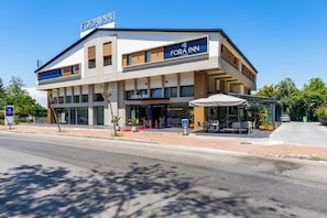 Un hôtel moderne doté d’un toit plat, de nombreux balcons et d’un espace extérieur aménagé et couvert.