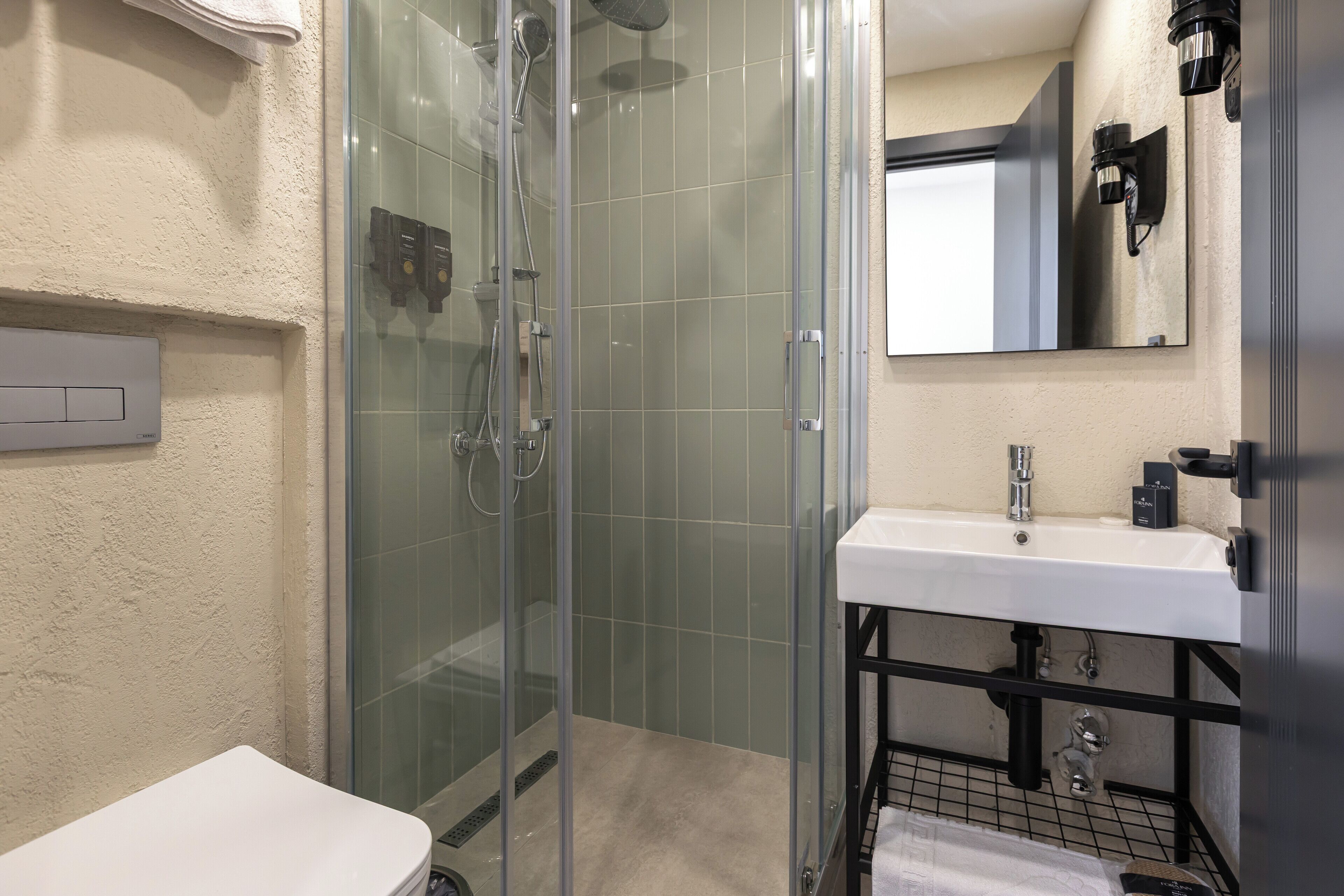A modern bathroom with a glass-enclosed shower, a white sink, and a mirror above the sink.