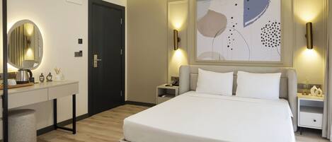 Un dormitorio moderno con una cama grande, mesitas de noche, un escritorio y un espejo.