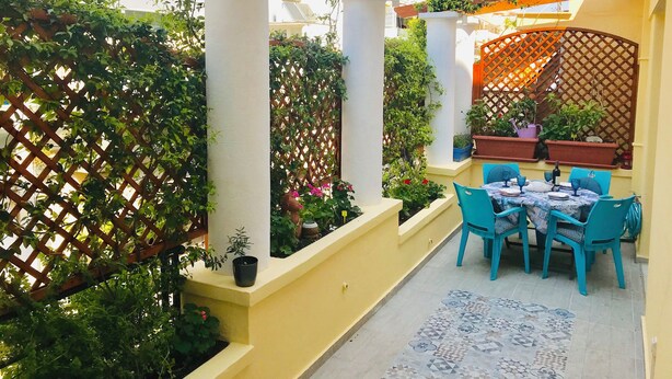 A patio with a table set for dining, surrounded by potted plants and a wooden lattice structure. - Jasmine in the heart of Kolonaki. (Αθήνα)
