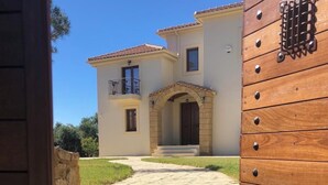 Una casa de dos pisos con una escalera de piedra que lleva a una puerta de madera con un aldabón metálico.