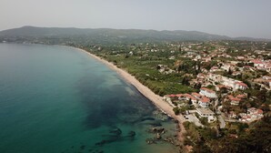 Un pueblo costero con una playa, edificios residenciales y colinas al fondo.