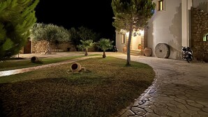 Un espacio exterior bien iluminado con un sendero empedrado, un muro de piedra y un edificio con fachada de piedra.
