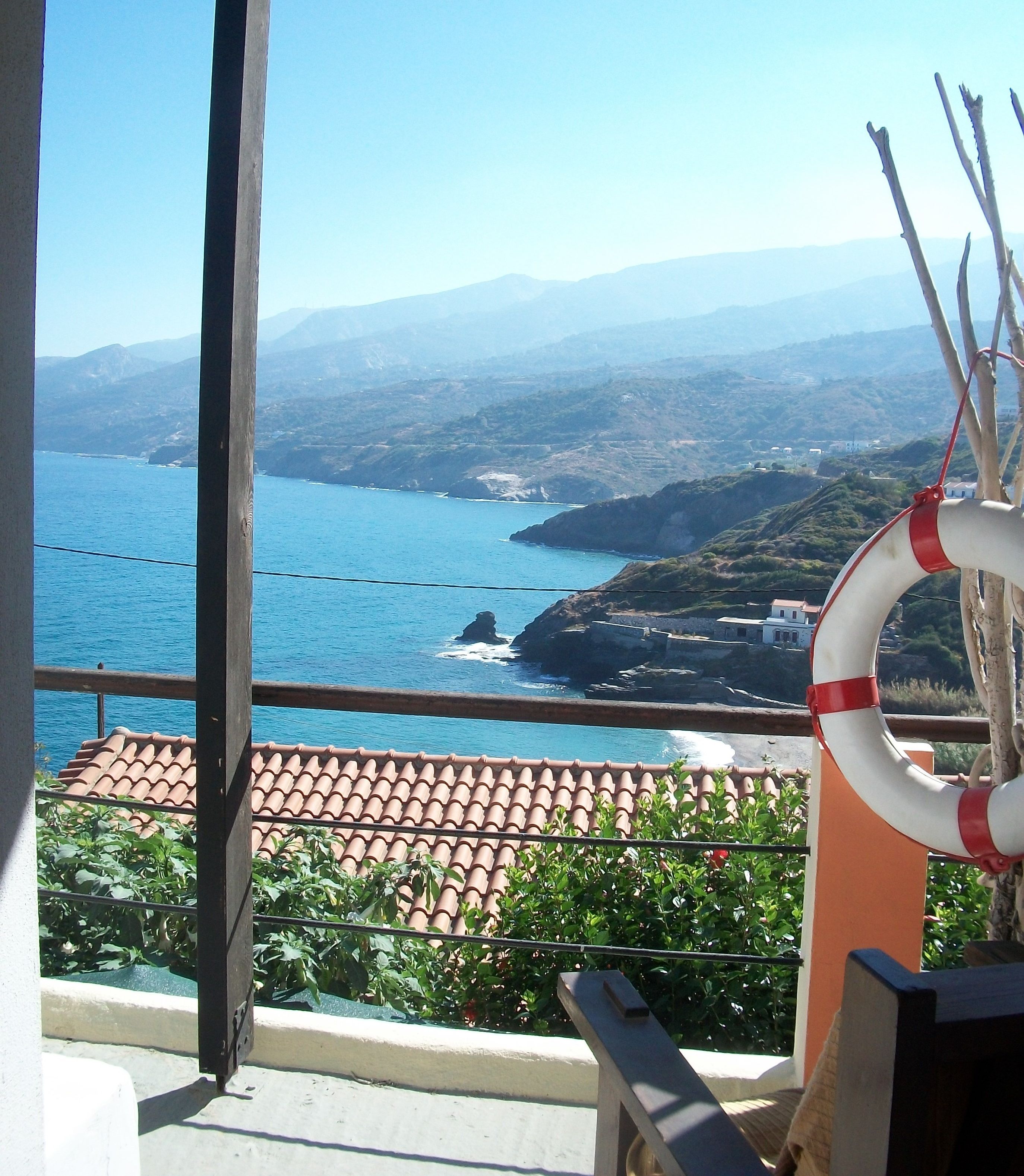 A balcony with a view of the sea and mountains.