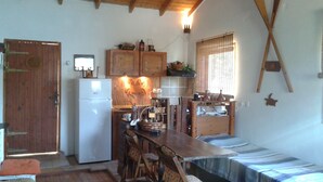 Una cocina compacta con armarios de madera, un refrigerador y una mesa de comedor con sillas.