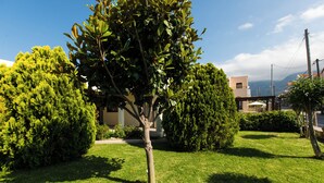 A well-maintained garden with a central tree, surrounded by neatly trimmed bushes and a lawn. - Eleanna villas. Villa Athena (Καβρός)