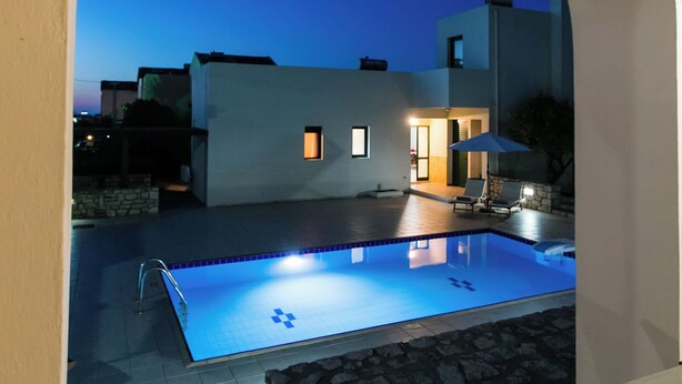 A swimming pool with a stone border, a lounge chair, and a small patio area with a stone wall. - Eleanna villas. Villa Athena (Καβρός)