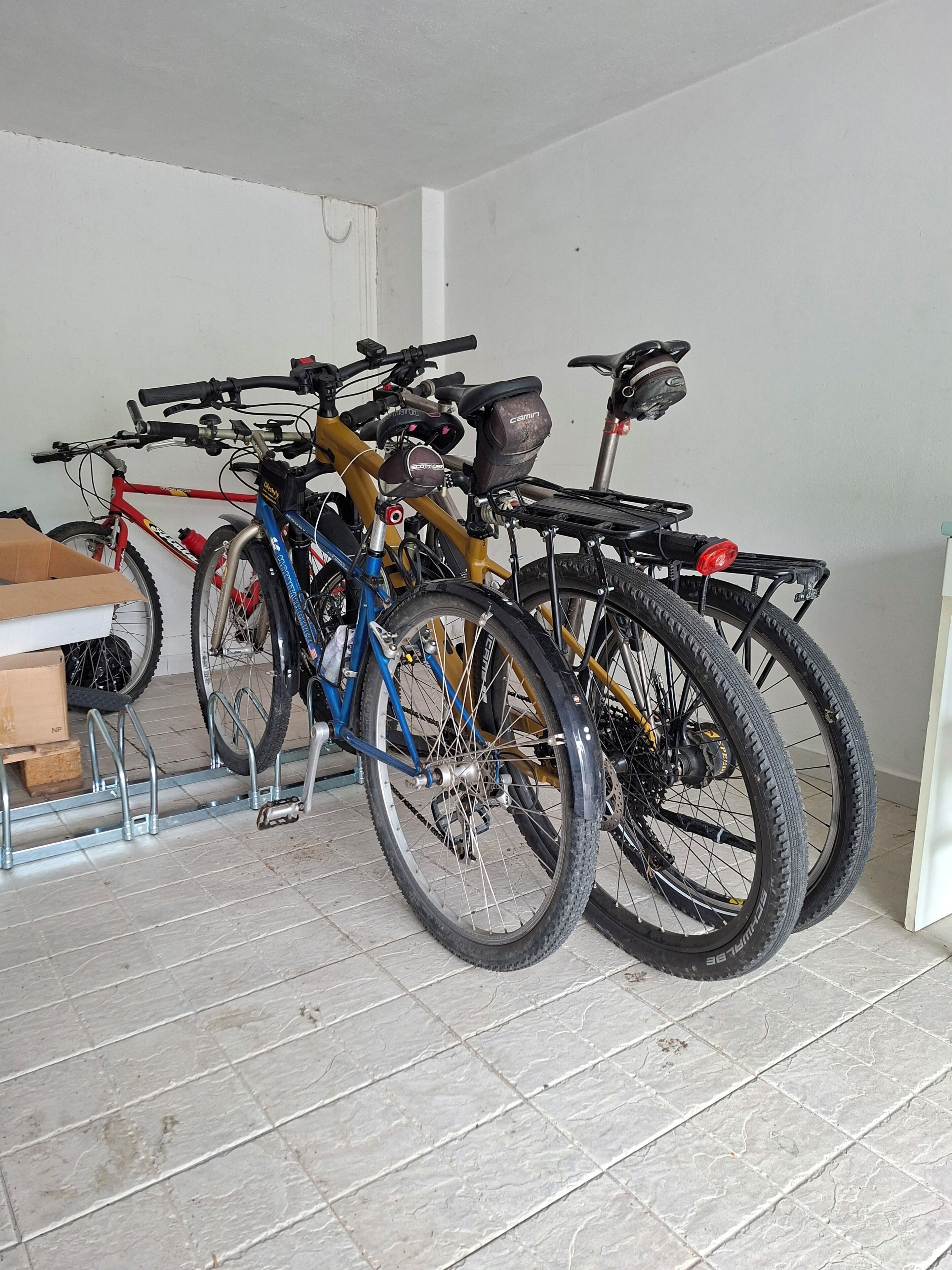 Bicicletas estacionadas en el interior, con piso de baldosas y paredes blancas.