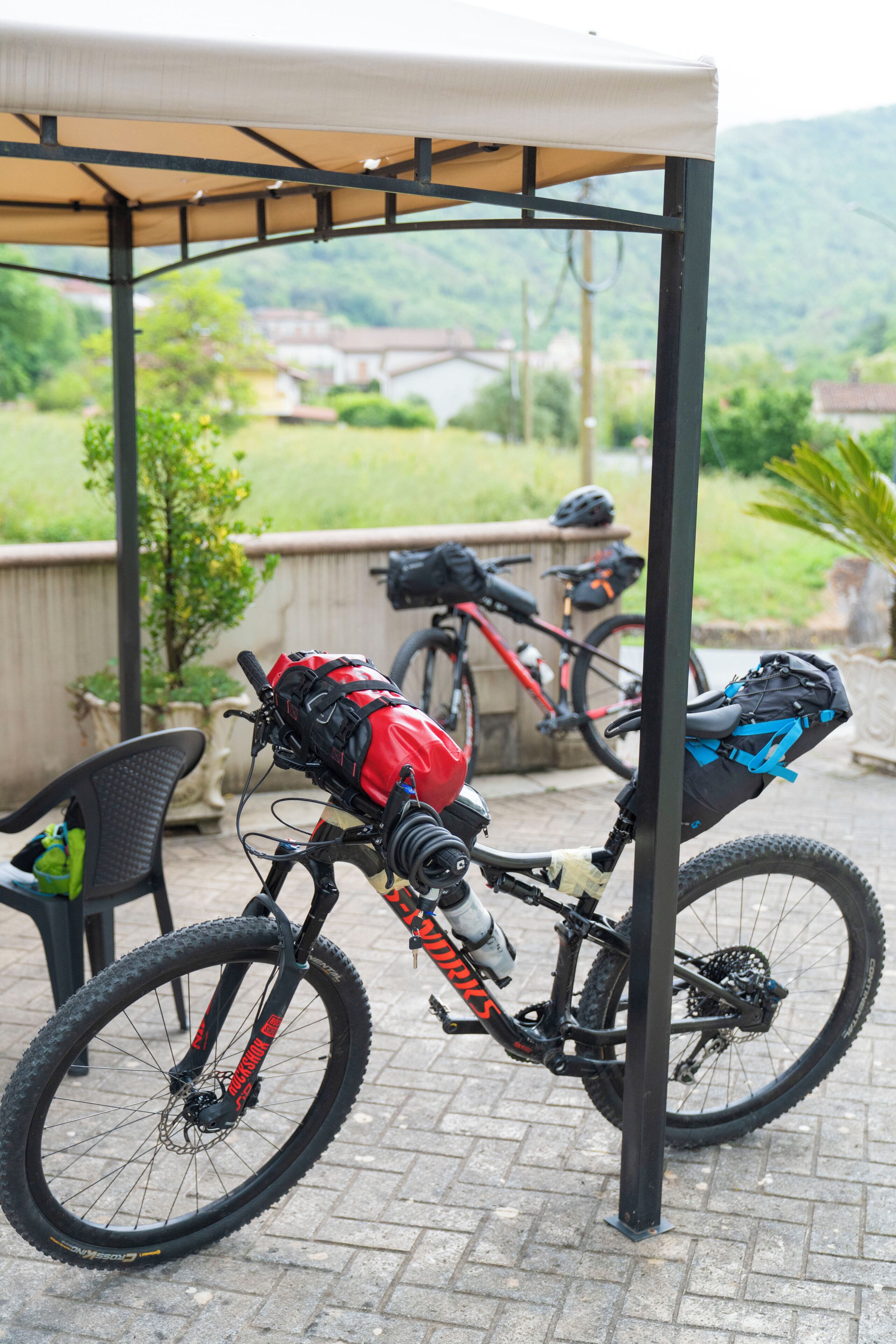 A bicycle parked under a covered area with a view of a green landscape in the background.