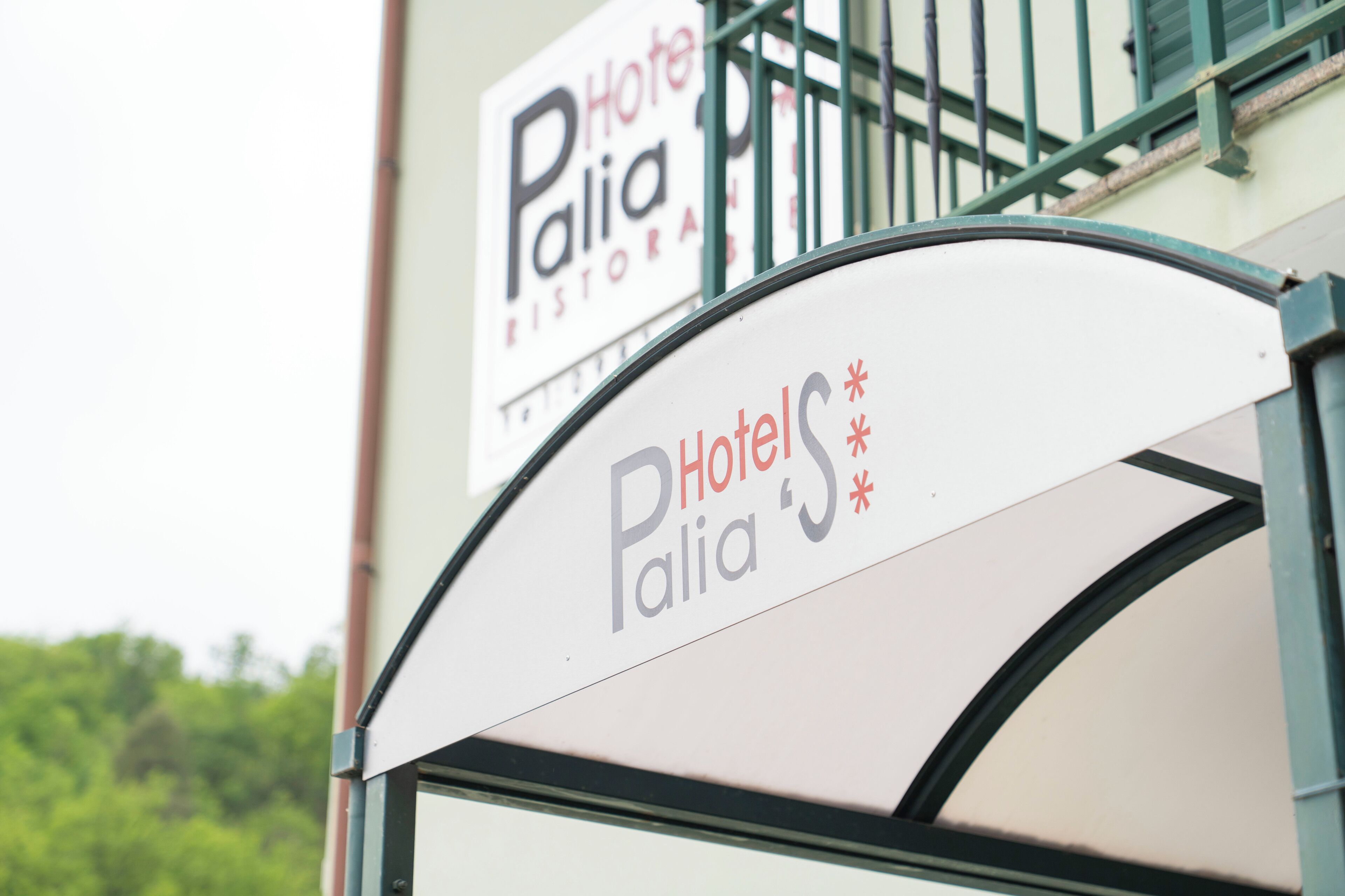 A hotel sign with the name 'Hotel Palia Ristorante' and a partial view of a building's entrance.