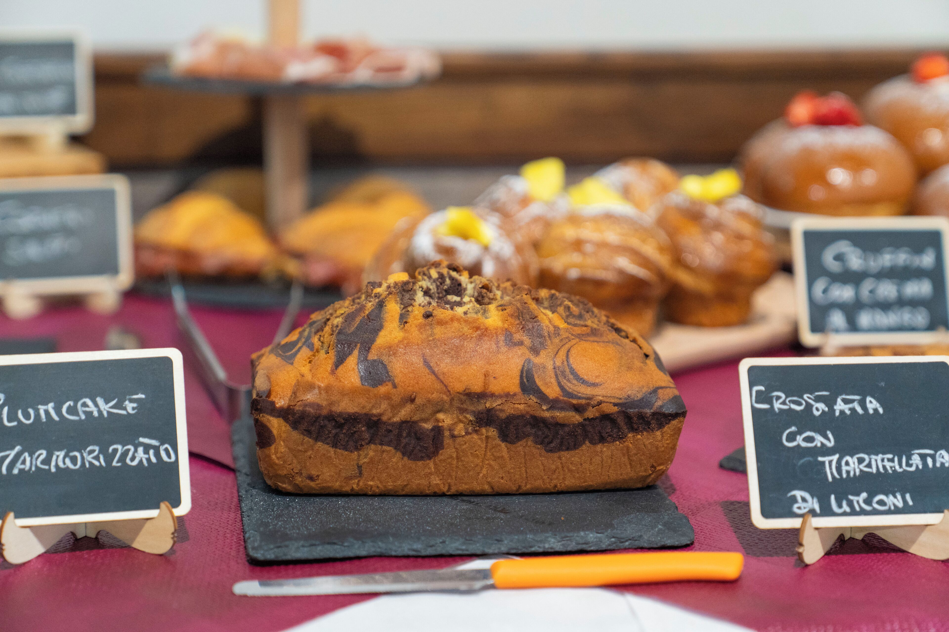 A loaf of bread with a dark crust, a knife, and two signs indicating different types of bread.
