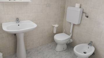 Ein Badezimmer mit einem Standwaschbecken, einer Toilette und einem Bidet.