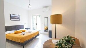 A modern hotel room with a bed, a desk, a lamp, and a plant. - Palia's Hotel (Laino Borgo)