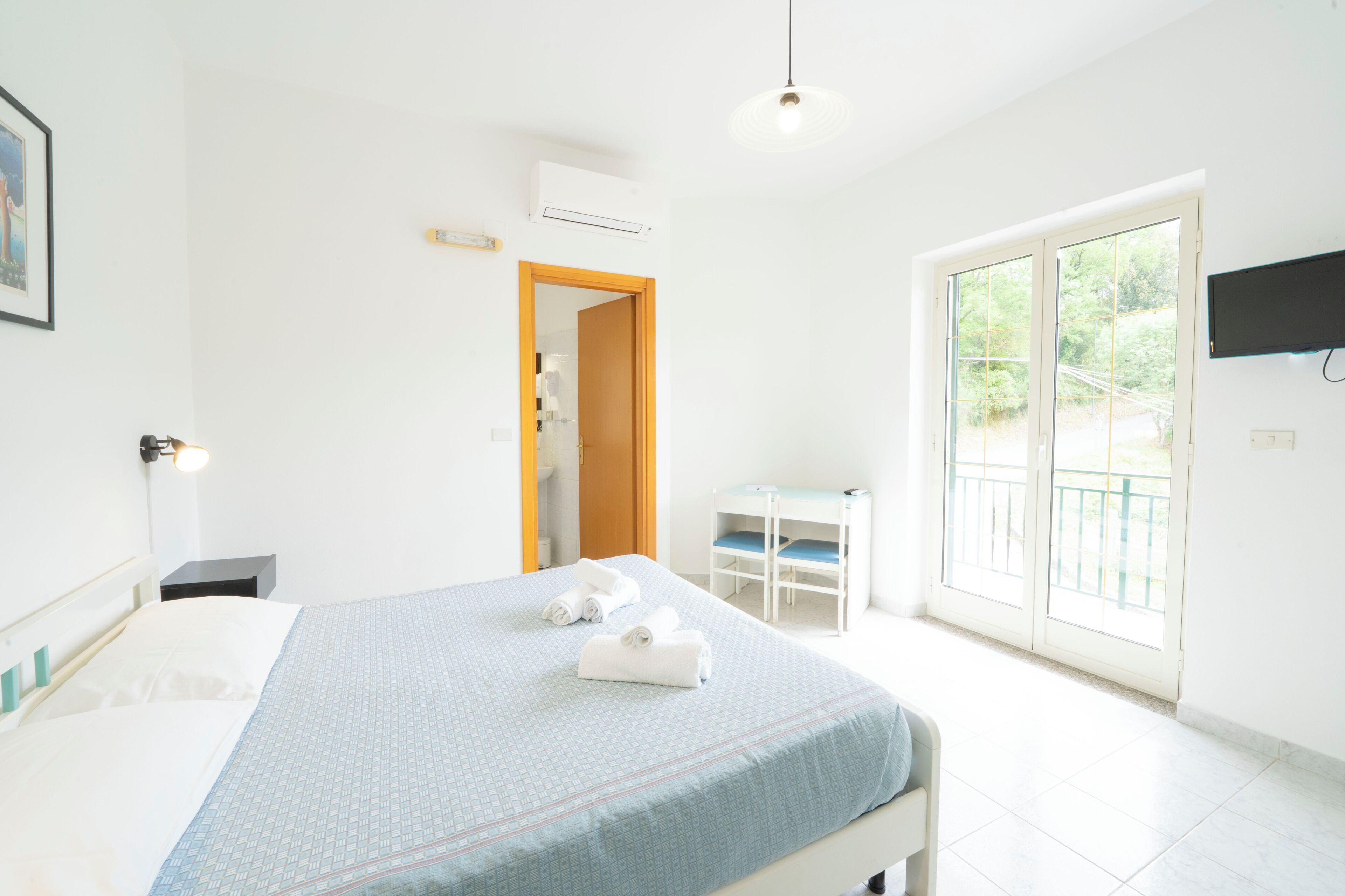 Une chambre d’hôtel avec un lit, un bureau, une chaise, une télévision et un balcon avec vue.