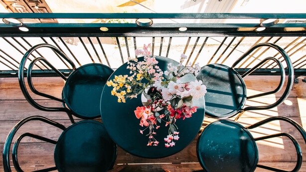A round table with a floral centerpiece surrounded by four green chairs. - Under the Clock Tower (Greek Traditional 125m² home) (Ναύπλιο)