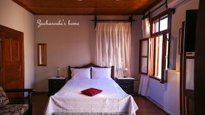 A bedroom with a large bed, wooden ceiling, and a window with curtains. - Under the Clock Tower (Greek Traditional 125m² home) (Ναύπλιο)