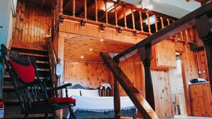 A wooden interior with a bed, rocking chair, and staircase. - Under the Clock Tower (Greek Traditional 125m² home) (Ναύπλιο)