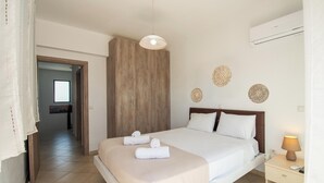 Una camera d'albergo con un letto, un comodino con una lampada, un armadio in legno e decorazioni a parete.