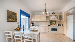 Una cucina con mobili bianchi, un tavolo da pranzo con sedie, un lampadario e un forno a microonde.