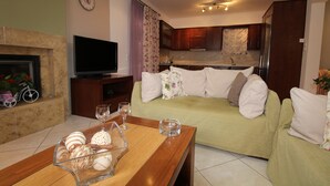 Ein Wohnzimmer mit einem grünen Sofa, einem Holztisch und einem Fernseher.