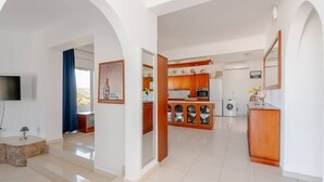 A spacious living area with a kitchen, a TV, and a dining area. - Aggeli Village House  (Ασκληπιείο)