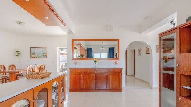 A spacious kitchen with wooden cabinets, a central island, and a large mirror. - Aggeli Village House  (Ασκληπιείο)