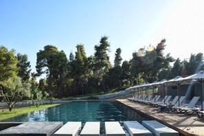 A pool area with lounge chairs and umbrellas, surrounded by trees. - Sani More & Sani Woods (Kassandra)