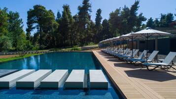 A swimming pool with steps leading into it, surrounded by lounge chairs and umbrellas.