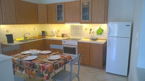 Une cuisine avec des meubles de rangement en bois, un réfrigérateur blanc, une table à manger avec des assiettes et une machine  à café.