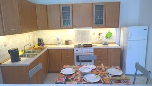 Une cuisine avec des meubles de rangement en bois, un évier, une cuisinière et une table mise avec des assiettes et des couverts.