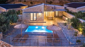 Eine moderne Villa mit Swimmingpool, Sitzgelegenheiten im Freien und einer Steinfassade.