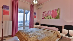 Un dormitorio con una cama grande, una mesita de noche, una lámpara, una ventana con cortinas y un cuadro de tulipanes.