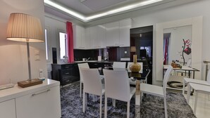 Una cocina moderna con armarios blancos, un comedor con sillas blancas y una alfombra negra.