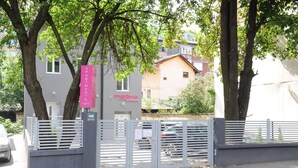 A gated apartment complex with a pink sign indicating 'Apartments' and 'Massimo Apartments'.