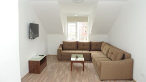 A modern living room with a brown sectional sofa, a small wooden coffee table, and a mounted TV.