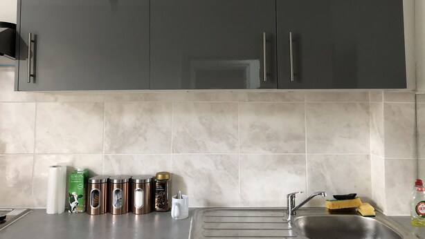 A kitchen with dark cabinets, a stainless steel sink, and various kitchen items on the counter. - Leman House (London)