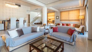 A spacious living area with two sofas, a coffee table, and a staircase leading to another level. - Vasiliki Villa with Private Pool (Ιαλυσός)