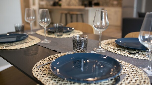 A dining table set with blue plates, clear wine glasses, and a patterned glass. - University Road Apartments (Belfast)