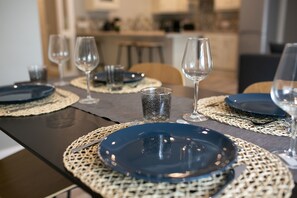 A dining table set with blue plates, clear wine glasses, and a patterned glass. - University Road Apartments (Belfast)