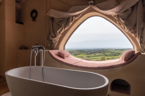 A bathtub with a view of a landscape through a window.