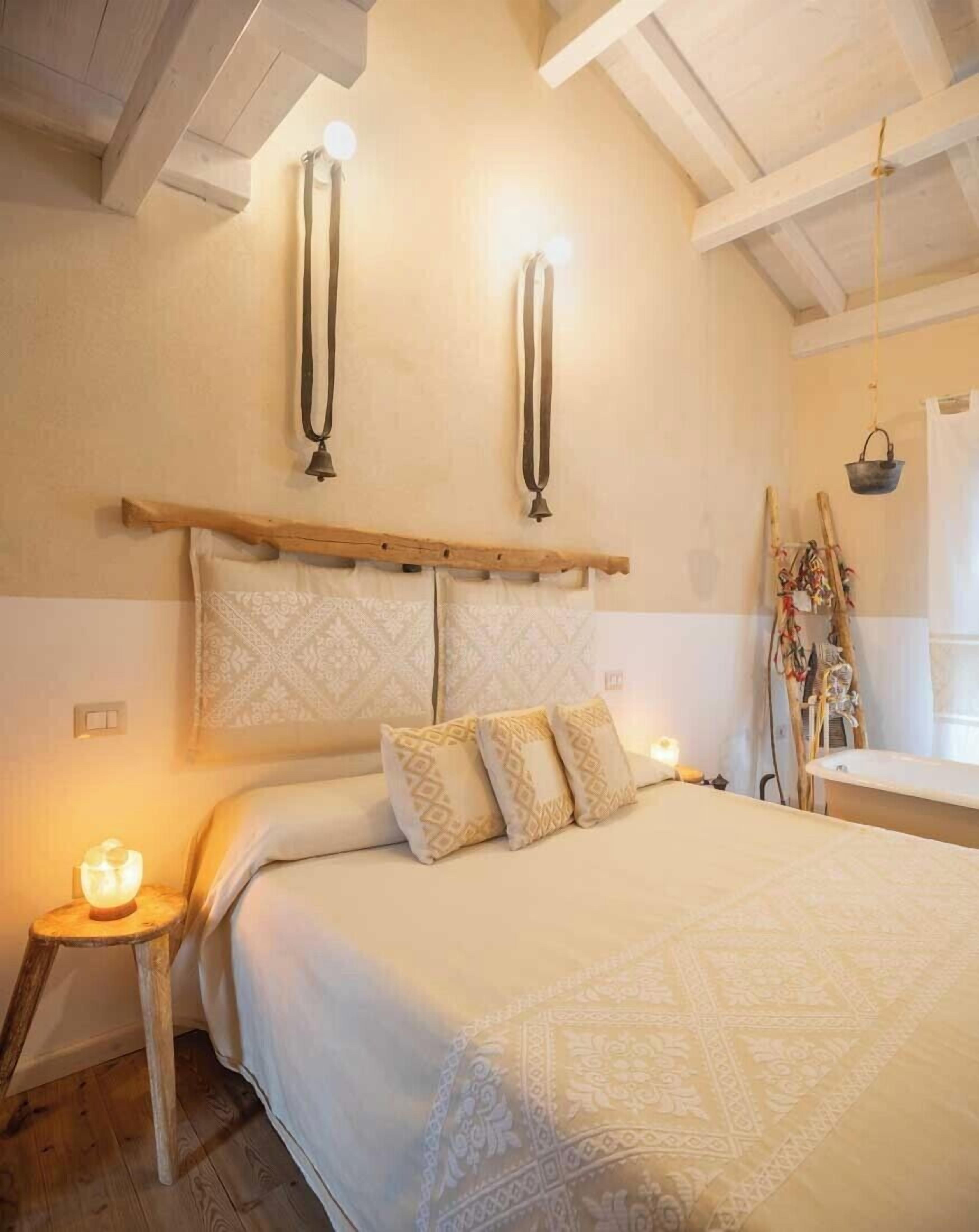 A bedroom with a bed, bedside lamps, a wooden headboard, and a nightstand with a lamp.