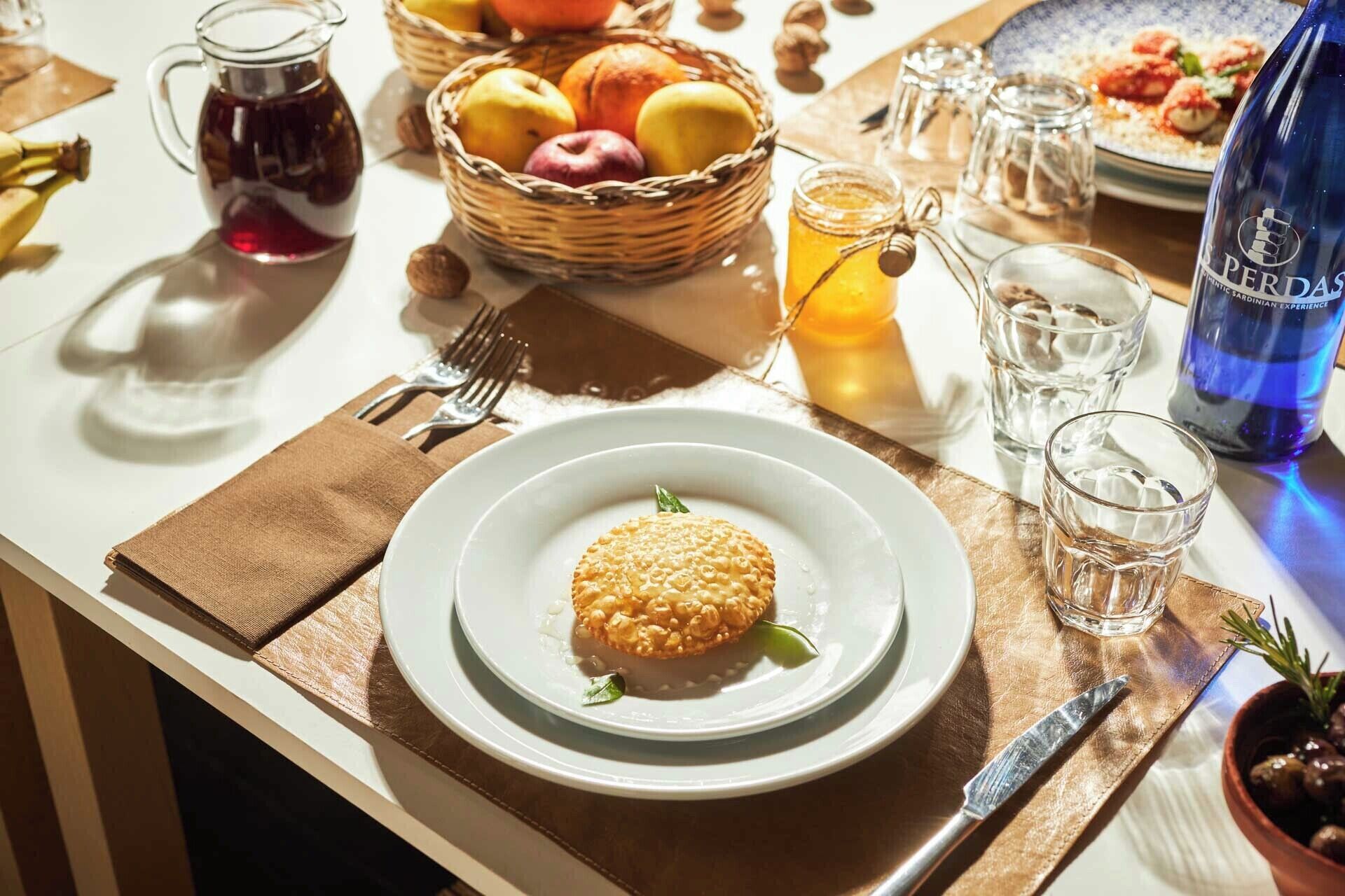 Ein Frühstückstisch mit Speisen, Obstkorb, Krug und Wasserflasche.