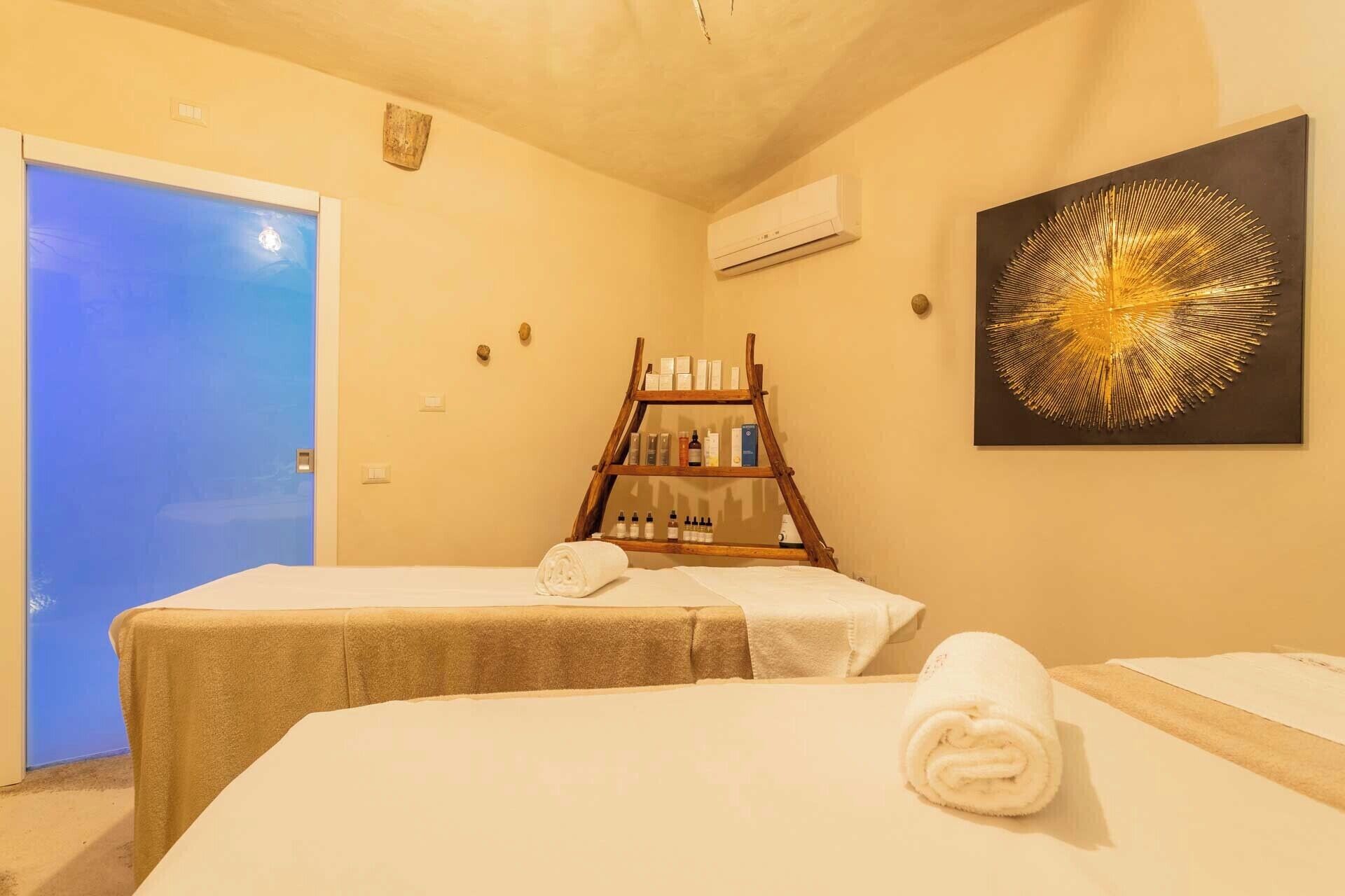 A room with two beds, a wooden shelf with toiletries, and a large abstract painting.