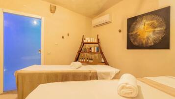 A room with two beds, a wooden shelf with toiletries, and a large abstract painting.