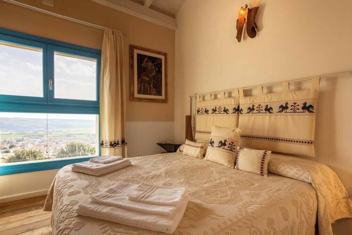 Ein Schlafzimmer mit einem großen Bett, Blick ins Grüne, einem Bild an der Wand und einem außergewöhnlichen Kopfteil.