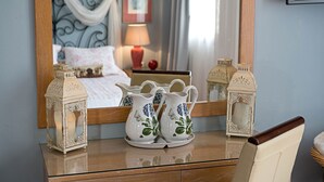 Une chambre à coucher avec un lit, une table de chevet ornée de vases décoratifs, un miroir et un téléviseur fixé au mur.