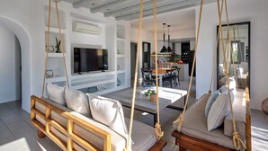 A modern living room with a wooden sofa, a TV, and a dining area with a kitchen in the background. - 𝐒𝐞𝐚𝐒𝐚𝐥𝐭 𝐃𝐫𝐞𝐚𝐦 𝐕𝐢𝐥𝐥𝐚, 𝐒𝐚𝐧𝐭𝐚 𝐌𝐚𝐫𝐢𝐚 𝟓 𝐦𝐢𝐧 𝐟𝐫𝐨𝐦 𝐍𝐚𝐨𝐮𝐬𝐚 (Νάουσα)