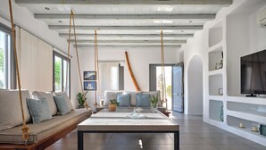 A spacious living area with a sofa, a coffee table, and a television on a white wall. - 𝐒𝐞𝐚𝐒𝐚𝐥𝐭 𝐃𝐫𝐞𝐚𝐦 𝐕𝐢𝐥𝐥𝐚, 𝐒𝐚𝐧𝐭𝐚 𝐌𝐚𝐫𝐢𝐚 𝟓 𝐦𝐢𝐧 𝐟𝐫𝐨𝐦 𝐍𝐚𝐨𝐮𝐬𝐚 (Νάουσα)